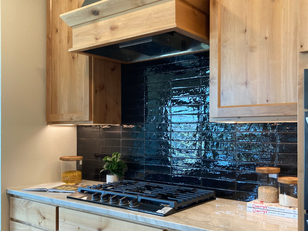 black tile backsplash in a kitchen with natural cabinetry
